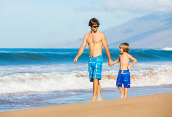 Happy father and son walking together at beach