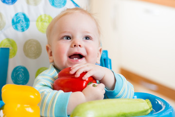 baby with vegetables sitting in chair on kitchen