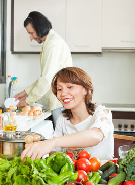 A man and a woman with a positive vegetables in the kitchen