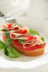 Bruschetta with prosciutto, tomato and basil.