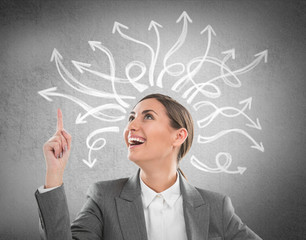 Happy, young businesswoman looking at many twisted arrows on the