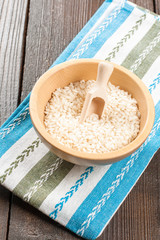 Rice in wooden bowl with ingredients for risotto