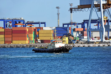 Container stack and tugboat under crane bridge