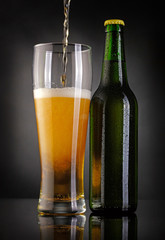 Glass and bottle of beer over black background
