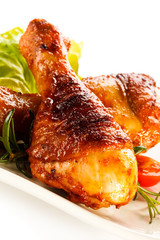 Grilled chicken legs and vegetables on white background