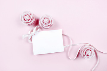 White paper card decorated with pink bow and rose scented candle