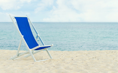 Lonely metal-framed deckchair on the beach. Space for text.