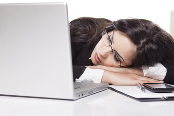 Tired young business woman sleeping on the desk with a laptop