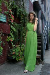 Young woman in green long dress walking outsige her home