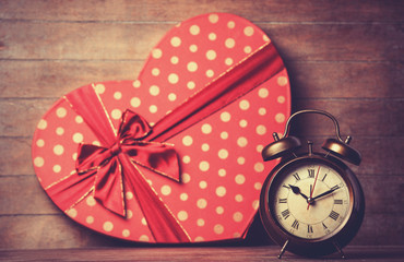 Retro clock and gift in heart shape on the background.