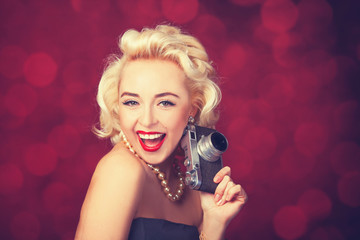 Beautiful blonde women with camera on red background.