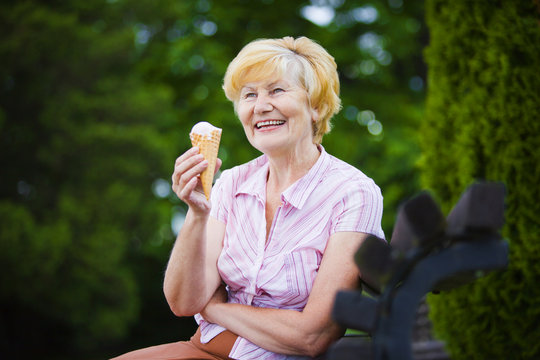 Grey-Haired Woman Relaxing with Ice-Cream on Bench in the Park