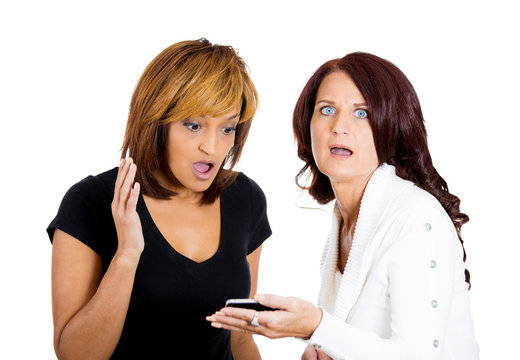 Two shocked women looking at phone seeing bad news or photos