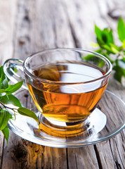 Transparent cup of green tea on wooden background