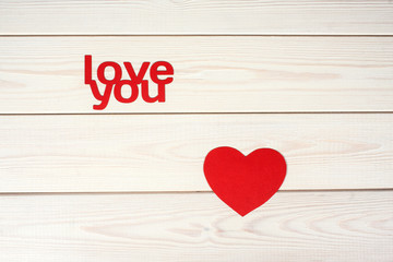 Red  heart symbol on a wood background with inscription  love yo