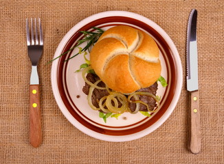 Grilled beef with onion rings in bun