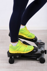 Woman doing exercise on stepper. Close-up on legs.