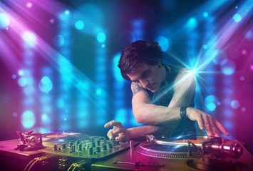 Obraz na płótnie Canvas Dj mixing music in a club with blue and purple lights