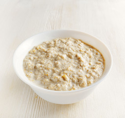 Bowl of oat porridge on wooden table