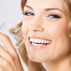 Fototapeta premium Young woman drinking water, on gray