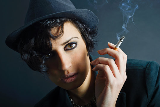 Brunette woman smoking a cigarette on black background wearing a
