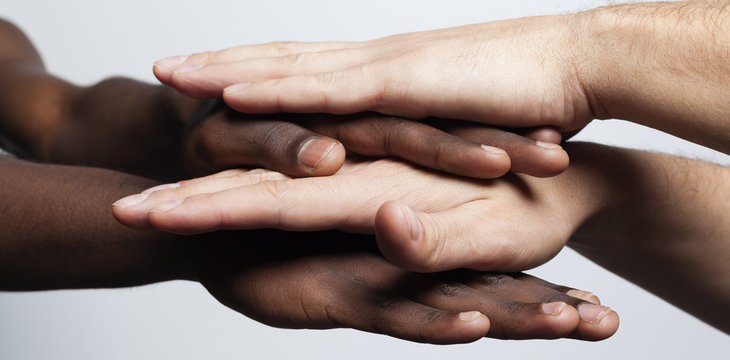 Multiracial hands together forming a pile over gray background