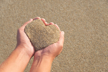 Hands holding a sand in form of heart
