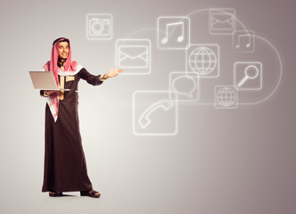 Young smiling arab with laptop shows virtual icons of the cloud