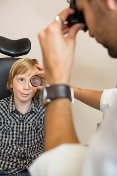 Boy Looking At Optician Examining His Eyes Through Lens