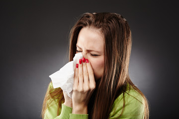 Caucasian female with flu blowing her nose