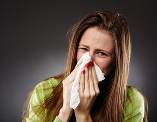 Caucasian female with flu blowing her nose