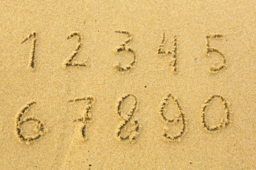 Numbers from one to ten written on a sandy beach.
