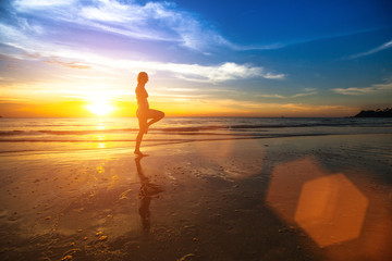 Silhouette of a young woman doing exercises at sunset.