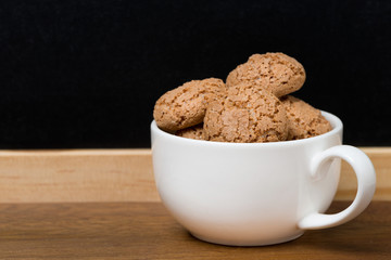 biscotti cookies in a cup on wooden table and black background