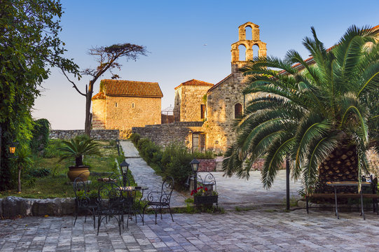 old town, square with stone buildings, an old church and a palm