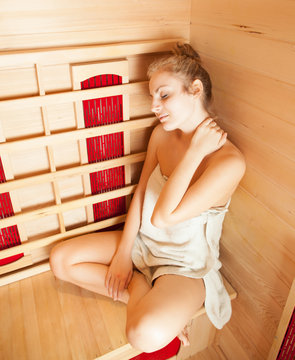 Young woman relaxing in a sauna (color toned image)
