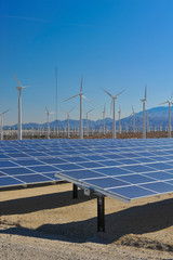 Solar panels in front of wind turbines and mountians