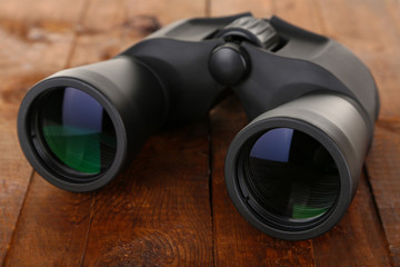 Black modern binoculars on wooden background