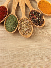Assortment of spices in wooden spoons on wooden background