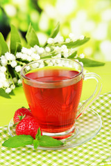 Delicious strawberry tea on table on bright background