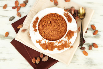 Cocoa powder in cup on napkin on wooden table