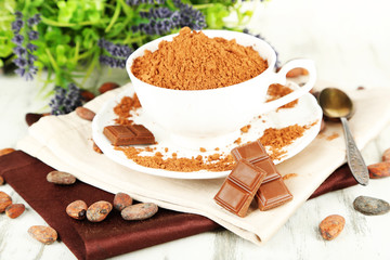Cocoa powder in cup on napkin on wooden table