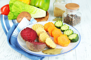Beautiful sliced vegetables, on plate, on wooden background
