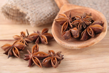 Star anise in wooden spoon, on wooden background