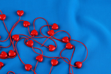 Heart-shaped beads on string on fabric background