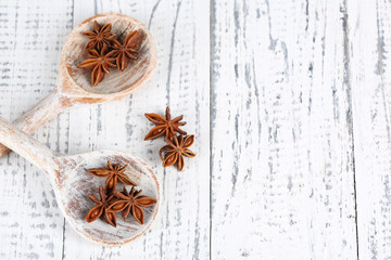 Star anise in wooden spoon, on wooden background