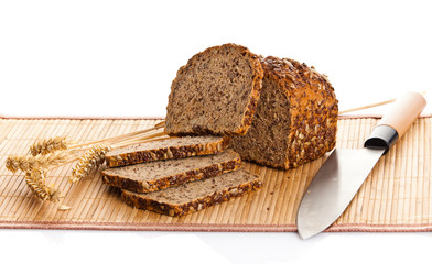 Fresh bread being sliced on a wooden cutting board with a bread