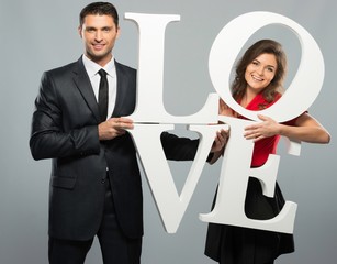 Beautiful smiling couple holding word LOVE