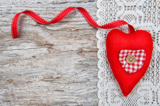 Valentine card with textile heart on lacy cloth and old wood