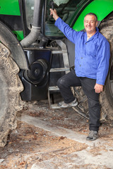 Obraz premium Farmer standing in front of his tractor